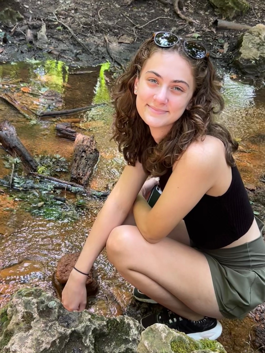 Tessa Sangermano smiles while standing in a stream outside.
