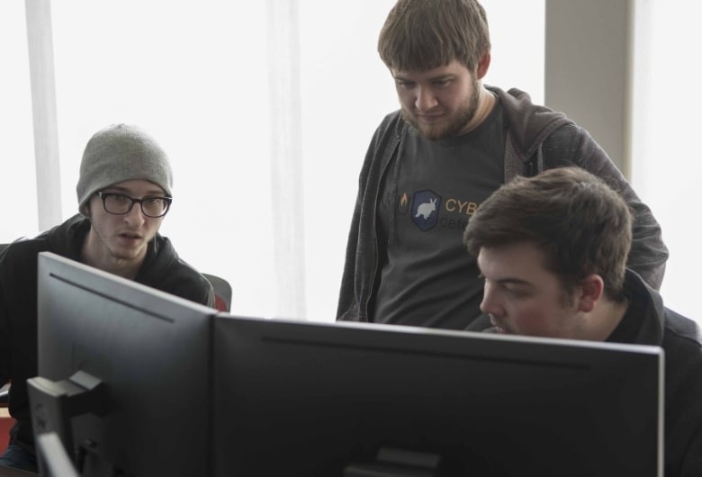 Group of students gathered around a computer workstation.