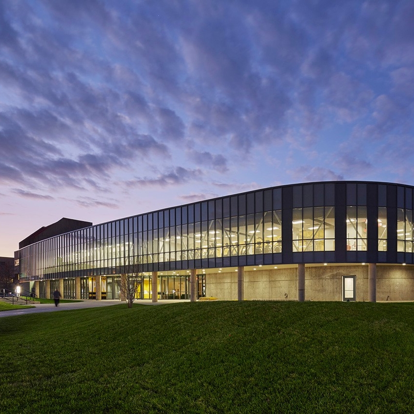 Campus recreation building lit up at dusk.