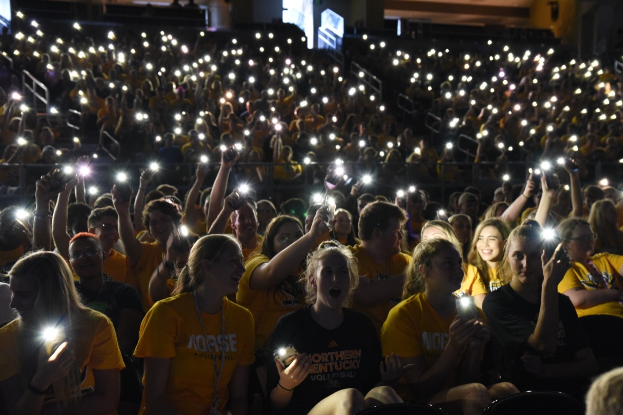 Students at convocation holding up phone flashlights